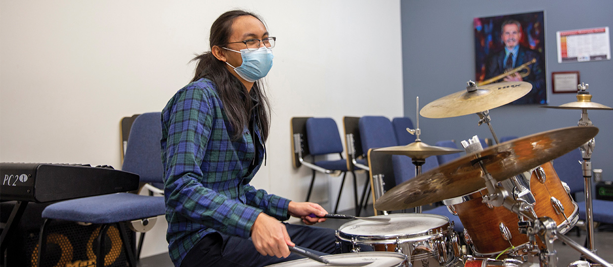 student playing drums in mask