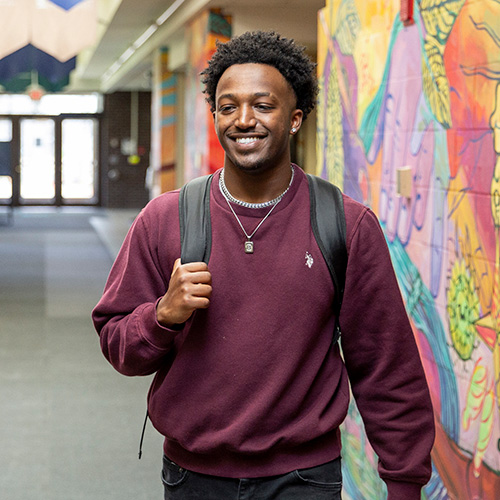 Beteab D. Tefera  ’22, Computer Science Transfer Pathway in hallway smiling at camera